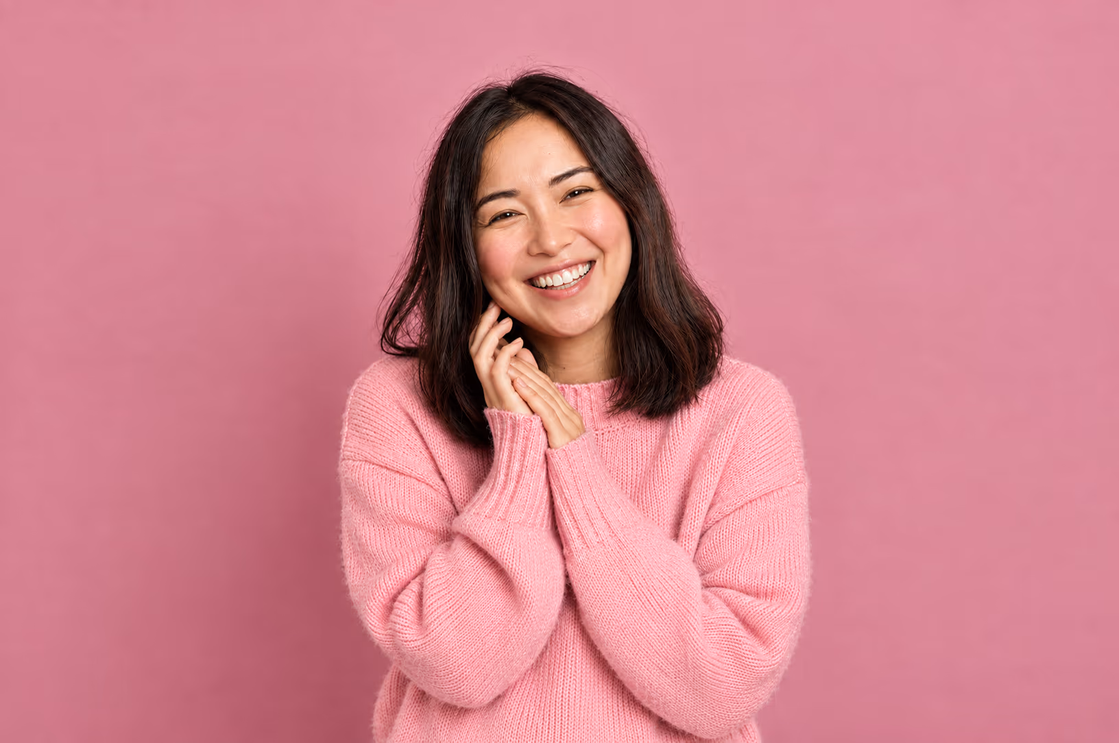 The same woman smiling, her hands together