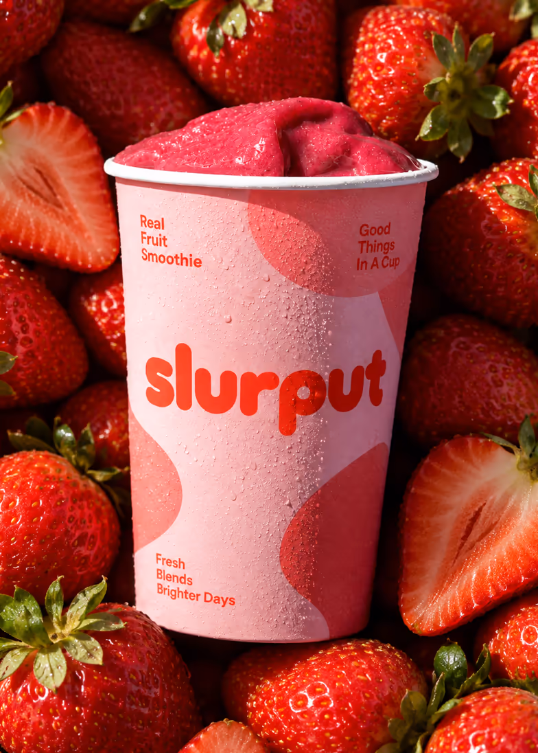 A Slurput cup surrounded by fresh strawberries